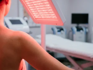 Roodlichttherapiepaneel dat warmrood licht uitstraalt op blote huid in een klinische behandelruimte.