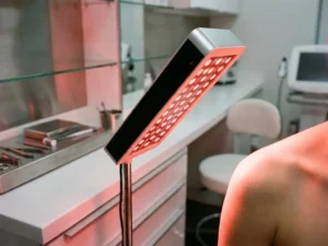 Roodlichttherapiepaneel dat warm rood licht uitstraalt op een gladde, gezonde huid in een klinische behandelruimte.